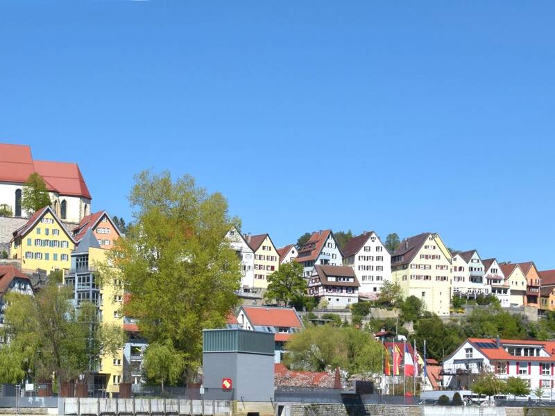 Blick auf eine historische Stadt mit Fachwerkhäusern und einer Kirche mit Turm unter klarem blauem Himmel.