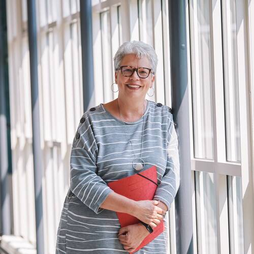 Portrait von einer Frau vor einem Gang mit Glasfront