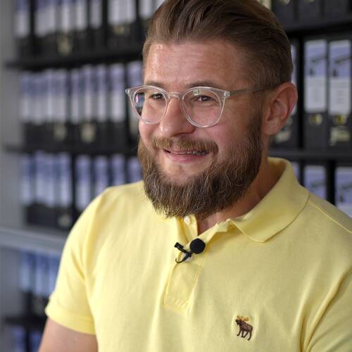 Lächelnder Mann mit einem Bart und einer Brille in ein Büro.