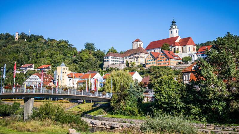 Horb am Neckar mit bunten Gebäuden und einer Kirche auf einem Hügel, umgeben von grüner Landschaft.