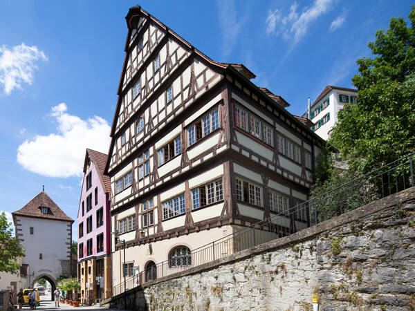Historische Gebäude, eine Mauer, ein Tor und ein blauer Himmel im Hintergrund.