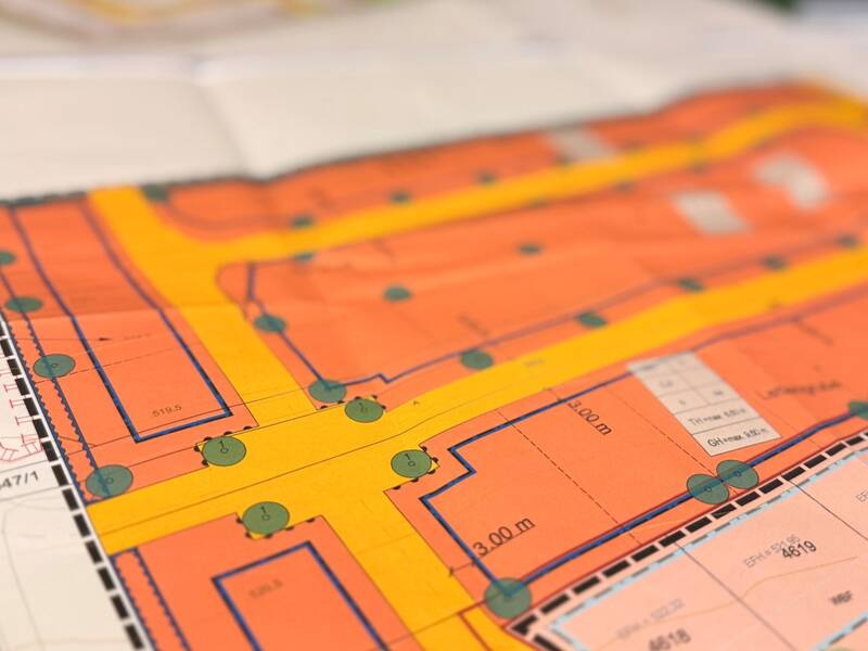 Ein bunter Stadtplan zeigt Straßen, Gebäude und markierte Bereiche in verschiedenen Farben und Schattierungen.