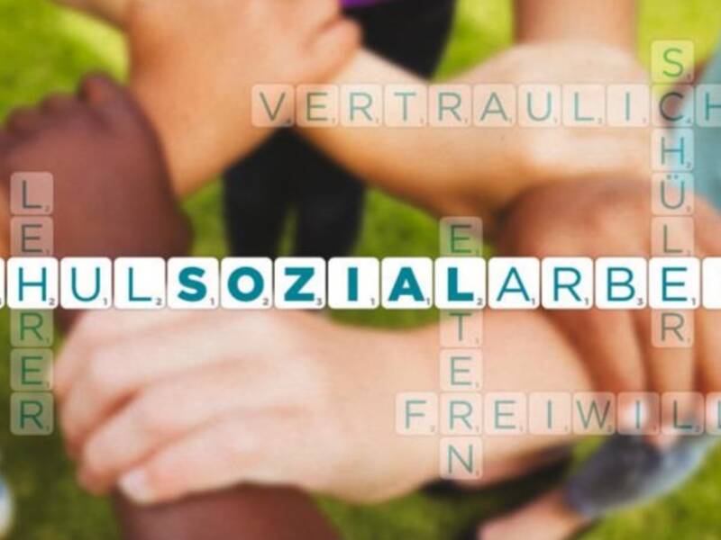 Mehrere Hände sind übereinander gelegt vor einem Hintergrund aus Scrabble-Steinen, die Wörter wie "Schulsozialarbeit", "vertraulich" und "freiwillig" bilden.