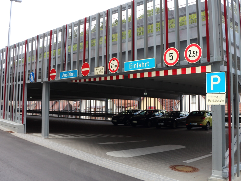 Einfahrt zu einem Parkhaus mit diversen Verkehrsschildern zur Höhen- und Gewichtsbeschränkung sowie zur Parksituation.