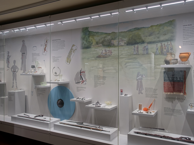 Eine Glasvitrine, in der Dinge ausgestellt werden mit Bildern und Beschreibungen.