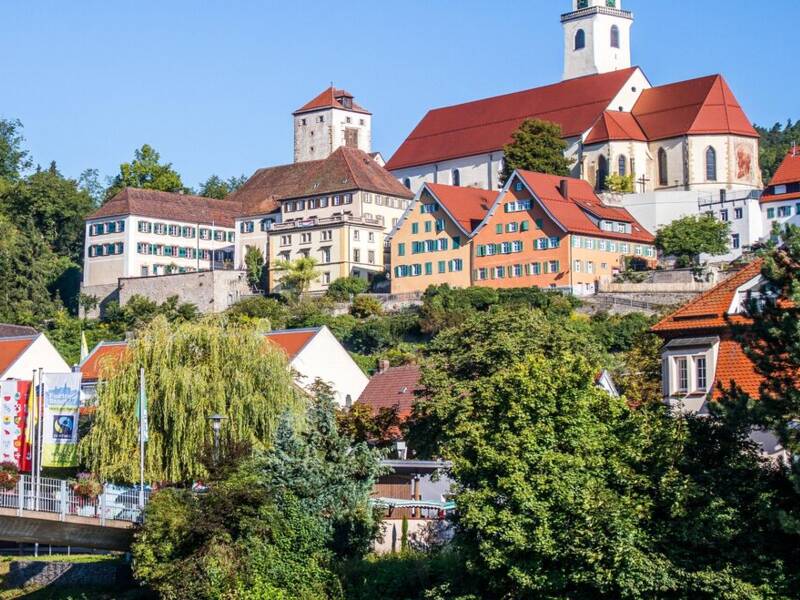 Horb am Neckar mit bunten Gebäuden und einer Kirche auf einem Hügel, umgeben von grüner Landschaft.