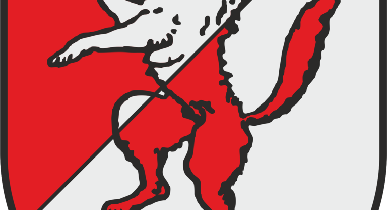 Ein Wappen zeigt einen weißen, aufrecht stehenden Wolf auf einem diagonal geteilten Hintergrund in Rot und Weiß.