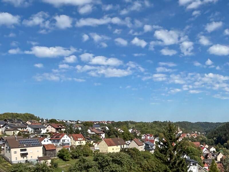 Ein malerisches Dorf mit traditionellen Häusern und einer Kirche, umgeben von üppigen grünen Wäldern.
