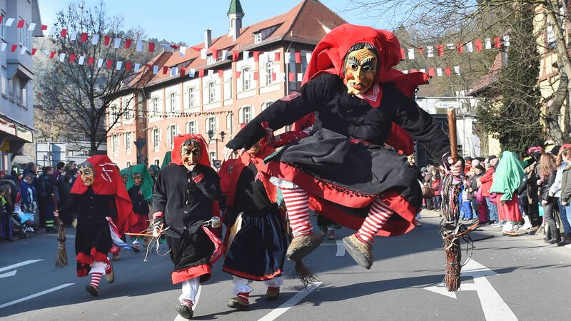 Personen tragen traditionelle Holzmasks während eines Festumzugs in einer deutschen Stadt.