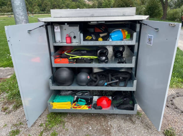 Das Bild zeigt einen offenen Schrank mit verschiedenen Sportgeräten.