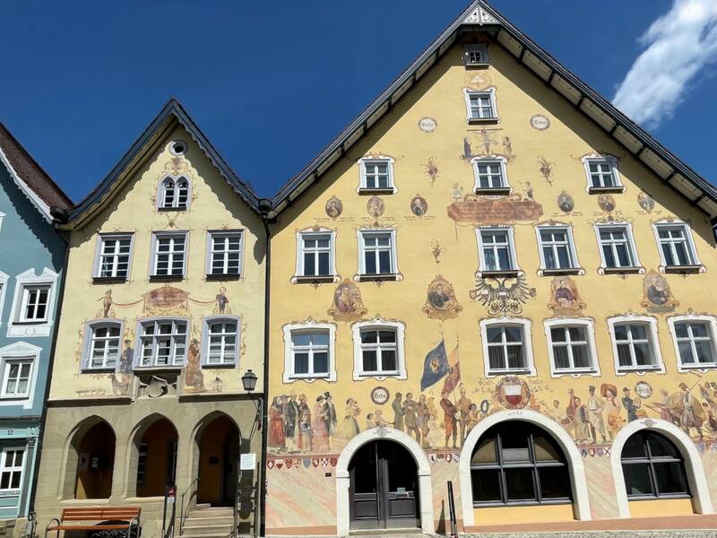 Mehrere historische Gebäude mit Fachwerk und Satteldach mit blauem Himmel und Sitzbank.