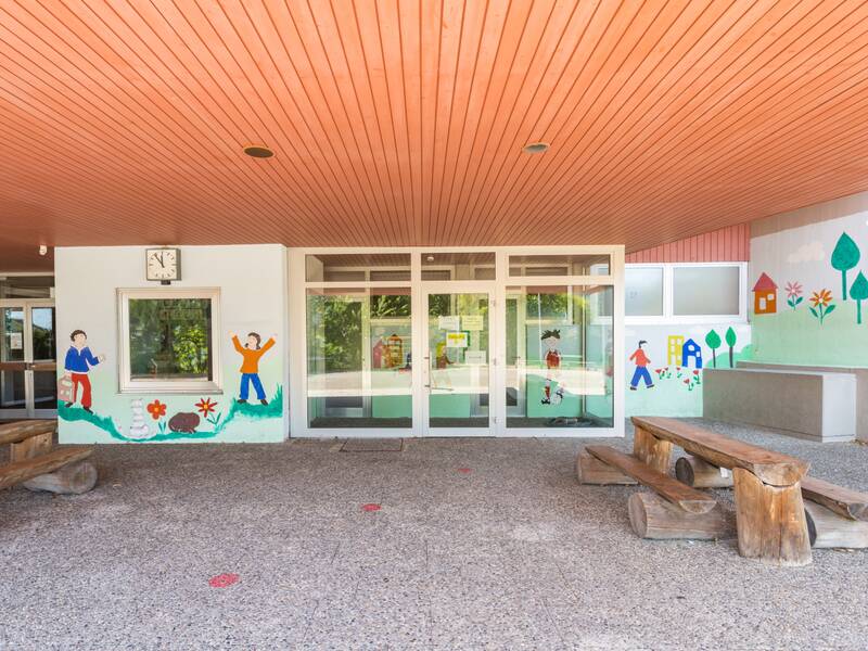 Das Bild zeigt den Schuleingang mit bunter Fensterdekoration.