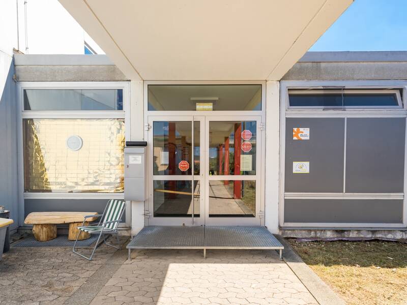 Das Bild zeigt den Schuleingang unter blauem Himmel.