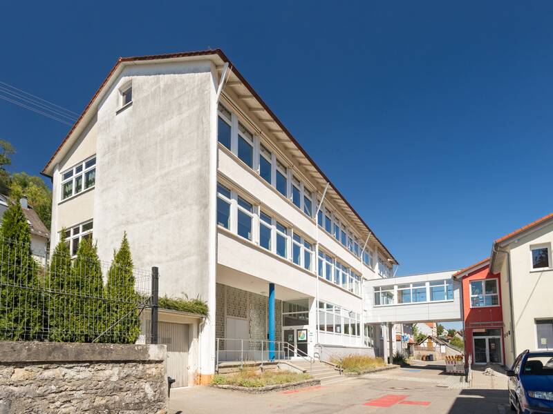 Das Bild zeigt das Schulgebäude mit dem Schulhof an.
