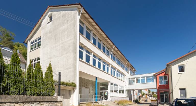 Das Bild zeigt das Schulgebäude mit dem Schulhof an.