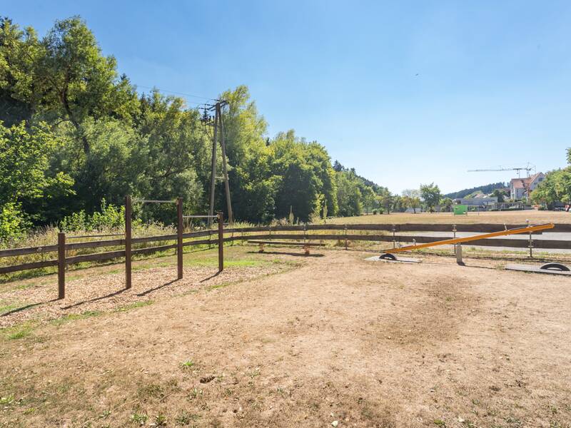 Das Bild zeigt den Schulhof mit Spielgeräten unter einem blauen Himmel.