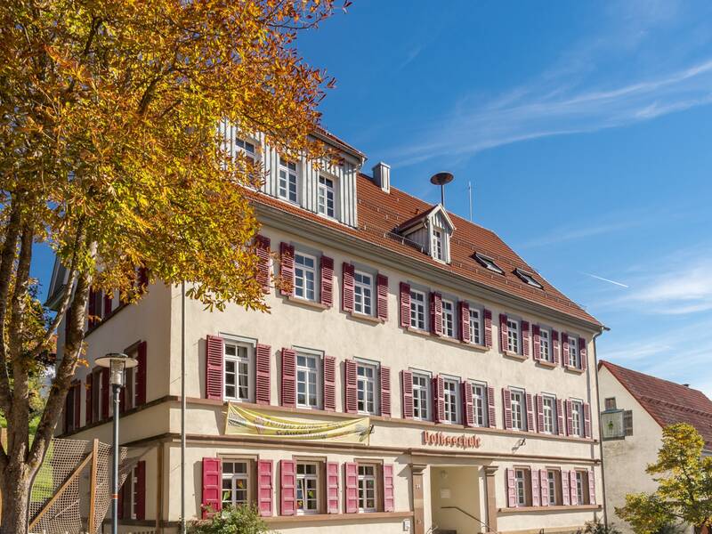 Ein großes Gebäude mit vielen Fenster und einem Schuleingang. 