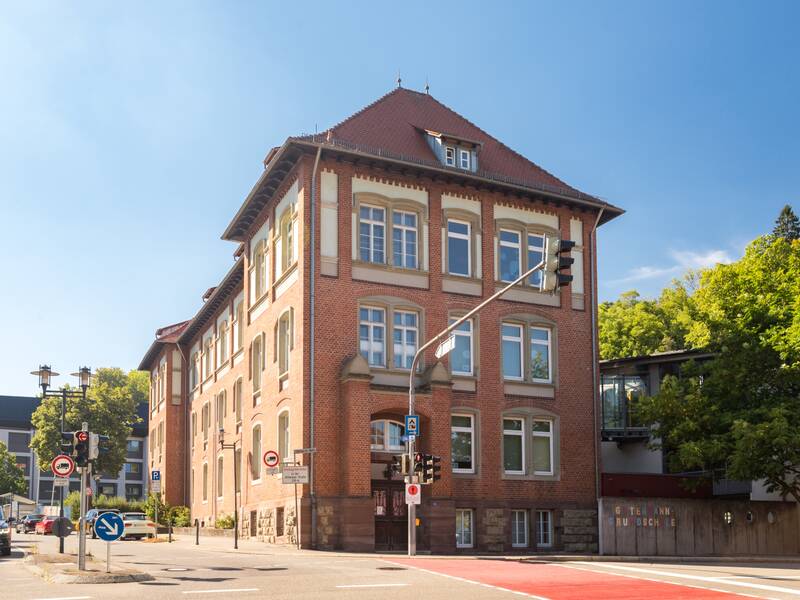 Das Schulgebäude mit der braunen Hausfassade.