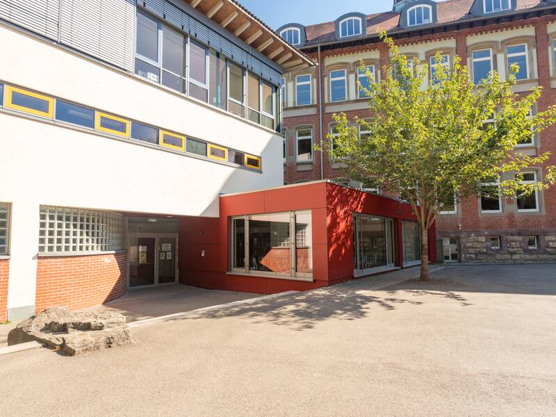 Das Bild zeigt den Schulhof unter einem blauen Himmel.