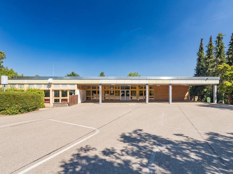 Ein überdachter Schuleingang unter blauen Himmel.