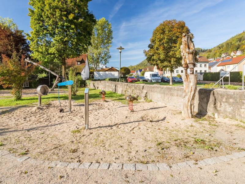verschiedene Wipptiere und Spielgeräte auf Sand auf einem Spielplatz im Wohngebiet 