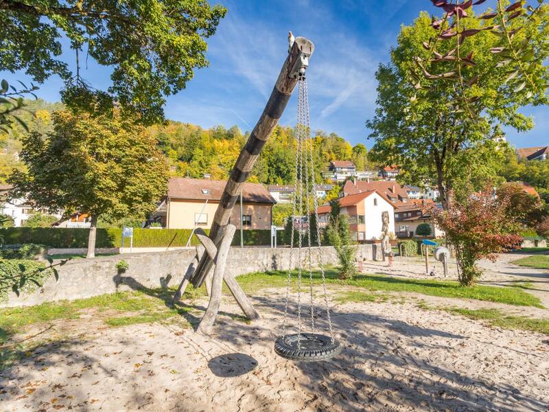 Reifenschaukel hängt von einem Holzbalken auf einem Spielplatz 