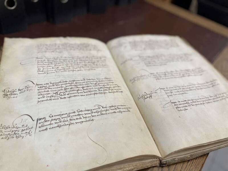 Geöffnete alte Handschrift mit handgeschriebenem Text und Anmerkungen auf vergilbtem Papier.