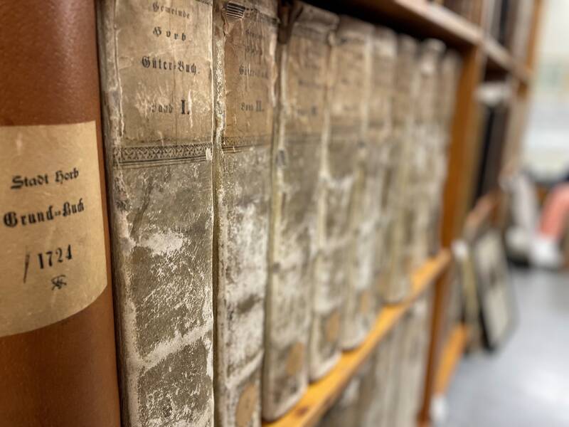 Reihe alter, abgenutzter Bücher mit braunen und schwarzen Einbänden auf einem Regal.