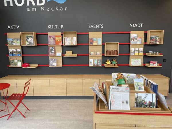 In einem Raum werden auf Holzregalen und Prospekte und Merchandise ausgestellt.