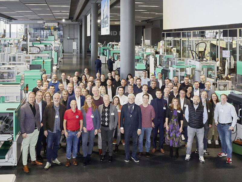 Auf dem Bild ist eine Gruppe von Menschen in einer Produktionshalle zu sehen.  
