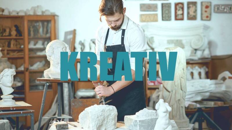 Ein Mann arbeitet in einer Werkstatt an einer Steinskulptur, umgeben von verschiedenen Kunstwerken, während das Wort "KREATIV" in großen Buchstaben eingeblendet ist.