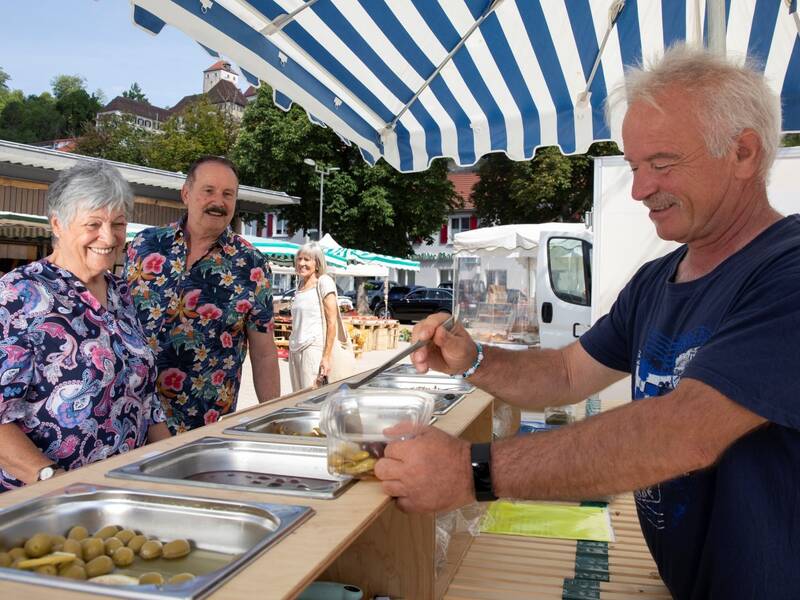Ein Mann verkauft an einem Stand etwas an zwei Personen.