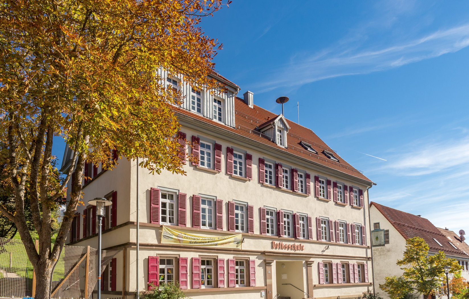 Ein großes Gebäude mit vielen Fenster und einem Schuleingang. 